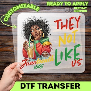 May include: A DTF transfer featuring a Black woman with curly hair, holding a drink. The design includes the text "THEY NOT LIKE US" in red, yellow, and green, and "June 1865". The transfer is customizable.