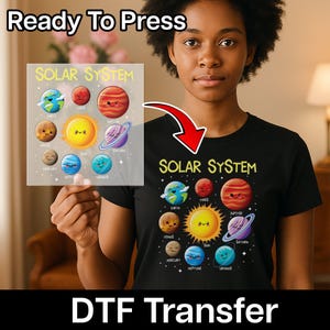 May include: Black t-shirt with a colorful "Solar System" graphic featuring planets and the sun. A DTF transfer with the same design is held up next to the shirt. The words "Ready To Press" and "DTF Transfer" are also visible.