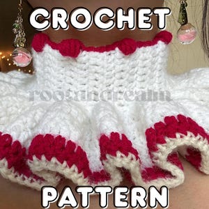 Puede incluir: Un cuello de ganchillo blanco con un borde con volantes adornado con hilo rojo brillante. El cuello presenta un diseño de cuello alto con pequeños detalles de pompones rojos a lo largo del borde superior. El texto CROCHET PATTERN está impreso.