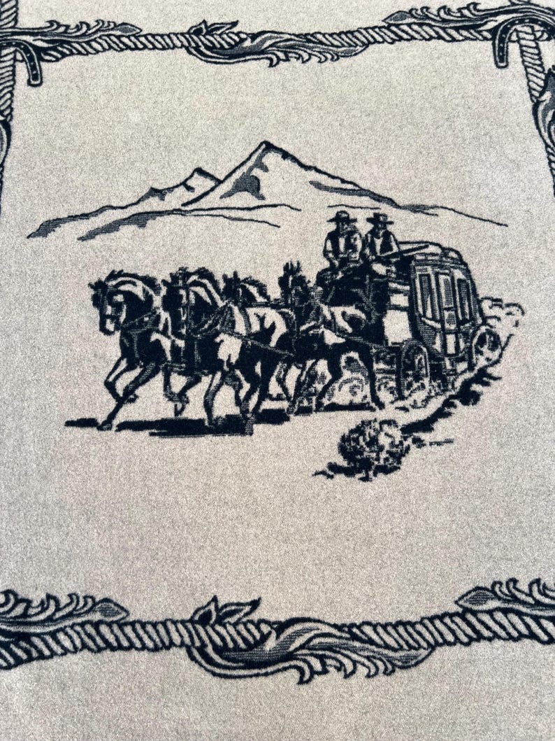 Op de afbeelding: Een lichtgrijs textiel met een donkerzwarte geweven illustratie van een postkoets getrokken door vier paarden, met twee figuren bovenop. De sc&egrave;ne bevat een bergketen op de achtergrond en een decoratieve rand van touw.