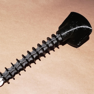 Puede incluir: Una herramienta negra impresa en 3D que presenta un eje largo y roscado similar a un tornillo con una serie de aletas circulares espaciadas uniformemente a lo largo, rematada con un mango negro sólido y contorneado y una punta blanca.