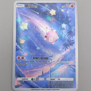 May include: A Pokémon trading card featuring a pink Minior character streaking across a starry sky. The card includes the text "Star Drop" and "HP 80". The card also has the text "This attack does 40 damage to 1 of your opponent's Pokémon."