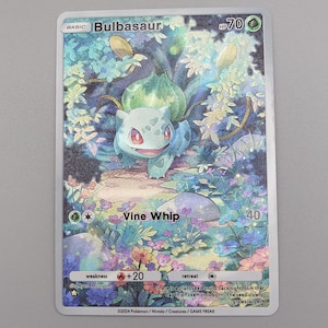 May include: A Bulbasaur Pokémon trading card featuring the character in a forest setting. The card has a green and blue color scheme with the text "Bulbasaur" and "Vine Whip". The card is surrounded by a white border.