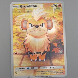May include: A Pokémon trading card featuring Growlithe, a cartoon dog-like creature with orange and white fur. The card has the text "Growlithe" and "Dig Claws". The card has a HP of 70.