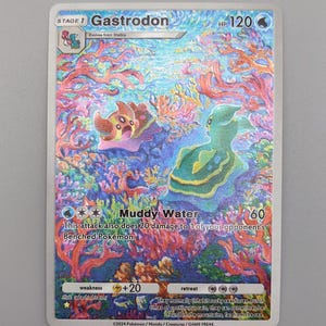 May include: A holographic trading card featuring the Pokémon Gastrodon. The card displays a colorful underwater scene with two Gastrodon characters. The card has the text "Muddy Water" and "120" on it.