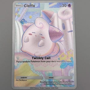 May include: A holographic Cleffa Pokémon trading card. The card features a pink Cleffa character with the text "Twinkly Call". The card has a HP of 30 and is set against a pastel background.