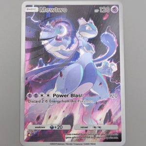 May include: A holographic Mewtwo Pokémon trading card. The card features a purple Mewtwo character with a Power Blast attack. The card has a 120 HP rating and includes text about the character's abilities and weaknesses.