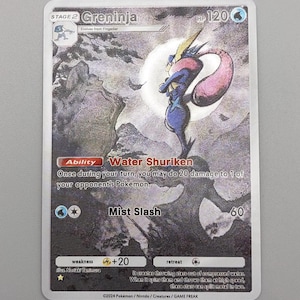Peut inclure: Carte de jeu Pokémon avec Greninja, un personnage bleu et violet, sur fond de clair de lune. La carte affiche le texte "Water Shuriken" et "Mist Slash", ainsi que les PV et autres détails du jeu.