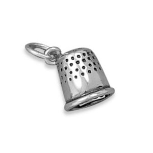 May include: A silver-colored thimble charm with a loop for attaching to a necklace or bracelet. The thimble has a classic shape with small, evenly spaced holes around the sides.