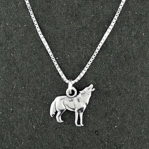 May include: A silver chain necklace with a small silver wolf pendant. The wolf is howling and standing on all four paws.