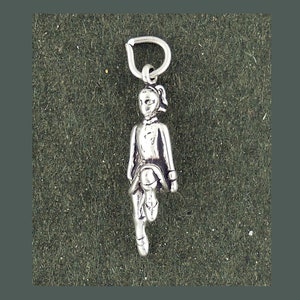 May include: Silver charm of a girl in a traditional Irish dance pose, wearing a kilt and holding a shoe in her hand.
