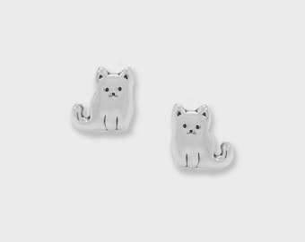 May include: A pair of silver-colored cat-shaped stud earrings. Each earring features a sitting cat with a rounded body, small ears, and a detailed face. The earrings are set against a plain white background.