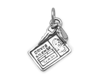May include: Silver charm in the shape of a driver's license with a key attached. The license has the words "DRIVER LICENSE" and a cartoon face.