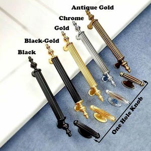 Può includere: Una selezione di ferramenta decorativa per mobili, tra cui maniglie e pomelli, in varie finiture: nero, nero-oro, oro, cromo e oro antico. L'immagine mostra una varietà di stili, tra cui pomelli a foro singolo e maniglie lunghe.