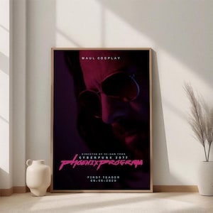 May include: A framed poster with a dark, futuristic theme. The poster features a close-up of a person's face with sunglasses, bathed in red and purple light. Text includes "MAUL COSPLAY" and "CYBERPUNK 2077 PHOENIX PROGRAM".