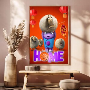 May include: A framed movie poster for the animated film "Home" featuring cartoon characters on an orange background. The title "HOME" is in large purple letters with an orange swirl. Red lanterns and fireworks are also visible.