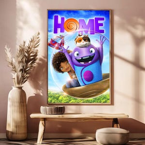 May include: A framed movie poster for the animated film "Home." The poster features a purple alien character with a cat on its head, a young girl, and a red car, all set against a blue sky with the word "HOME" in large purple letters.