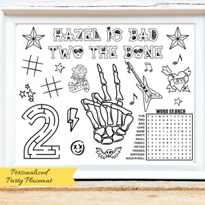 以下が含まれることがあります： 「HAZEL IS BAD TWO THE BONE」のテキストが入った、白黒のフレーム付きパーティープレースマット。 骸骨の手、星、バラのタトゥー、迷路、ワードサーチ、その他のグラフィックが含まれています。 下部のバナーには「Personalized Party Placemat」と書かれています。