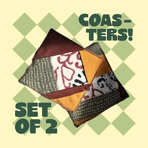 May include: A set of two square fabric coasters featuring a patchwork design with brown, mustard yellow, and white sections. The white fabric has a dark red abstract pattern, while other sections have textured stitching. Text reads COASTERS! SET OF 2.
