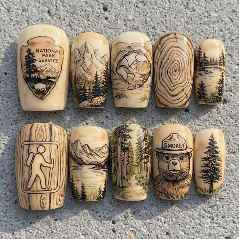 May include: A collection of ten wooden nesting dolls, each hand-painted with nature-themed designs. The dolls feature images of mountains, forests, Smokey Bear, and the National Park Service logo. The dolls are beige with brown and green accents.
