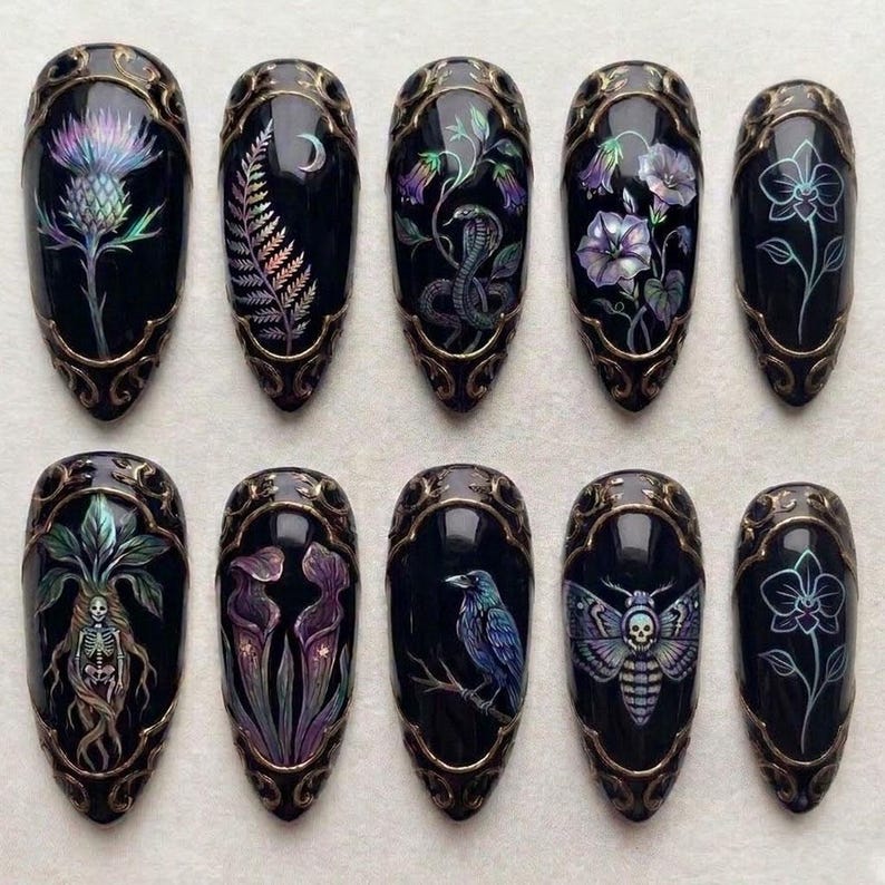 May include: Set of ten black, almond-shaped press-on nails with intricate gothic-inspired designs. Each nail features a different illustration, including flowers, a snake, a raven, and a moth with a skull, all framed with a gold filigree border.
