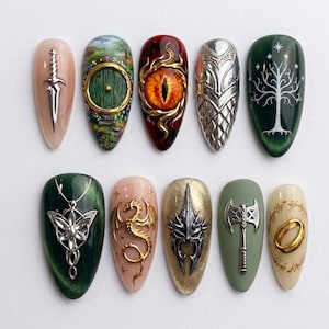 Op de afbeelding: Tien amandelvormige kunstnagels met gedetailleerde fantasy-ontwerpen. De set bevat een zilveren dolk, een ronde groene deur, een vurig oog, een zilveren harnas, een witte boom, een zilveren hanger, een gouden draak, een zilveren helm, een bijl en een gouden ring.