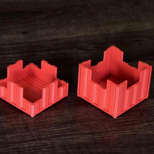 May include: Two red, square-shaped containers with crenelated, castle-like walls. The containers feature vertical ribbed detailing on the exterior sides and a flat base. One container is shorter than the other, and both have open tops.