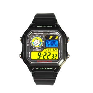 May include: A black Casio digital watch with a resin strap. The face features a yellow digital display showing 9:22:32, a world map graphic, and a circular icon of a cartoon character. Text includes WORLD TIME, 5 ALARMS, WR100M, and ILLUMINATOR.