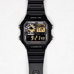 May include: Black digital watch with a rectangular face and black band. The watch face displays the time, date, and various functions. The watch has the word "CASIO" on the face.