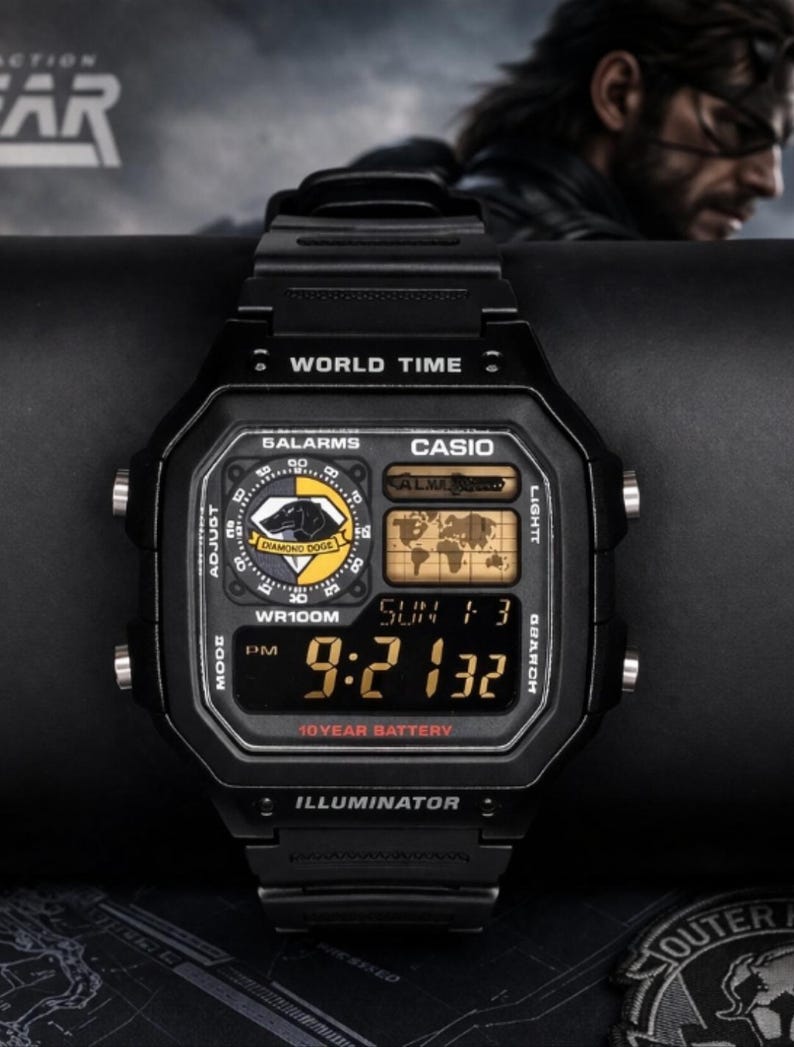 May include: Black Casio digital watch with a rectangular face. The watch displays the time, date, and world time functions. Features include "WORLD TIME", "5ALARMS", and "ILLUMINATOR" text. The watch has a 10-year battery.