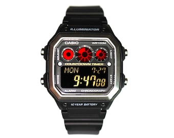 Può includere: Un orologio da polso digitale nero con quadrante quadrato, recante le scritte CASIO, ILLUMINATOR, WR100M, COUNTDOWN TIMER, ALARM, CHRONOGRAPH e 10 YEAR BATTERY. Il display mostra MON 7-27 e 9:47:08 con tre indicatori grafici circolari rossi.