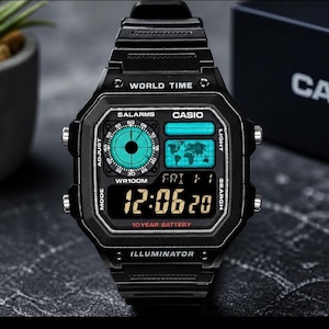 Op de afbeelding: Zwarte digitale Casio-horloge met een rechthoekige wijzerplaat. Het horloge toont de tijd, datum en wereldkaart. Functies omvatten 5 alarmen, een licht en een batterij van 10 jaar. Het horloge is waterdicht tot 100 meter.