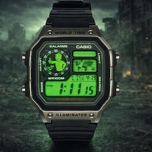 May include: A black digital wristwatch with a metallic bezel and a bright green display. The screen features a world map, a digital time readout, and a circular graphic of a cartoon character giving a thumbs up. Text includes CASIO, WORLD TIME, 5 ALARMS, WR100M, 10 YEAR BATTERY, and ILLUMINATOR.