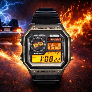 Könnte beinhalten: Eine schwarze und goldfarbene Casio Digitaluhr mit dem Text "Back to the Future" auf dem Zifferblatt. Die Uhr zeigt die Zeit 13:08 Uhr an. Die Uhr hat ein schwarzes Armband und ein goldfarbenes Gehäuse.