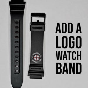 May include: Two black watch bands are displayed against a gray background. One band has a series of holes, and the other has a buckle and a circular logo with the text "Umbrella Corporation". The text "ADD A LOGO WATCH BAND" is also visible.