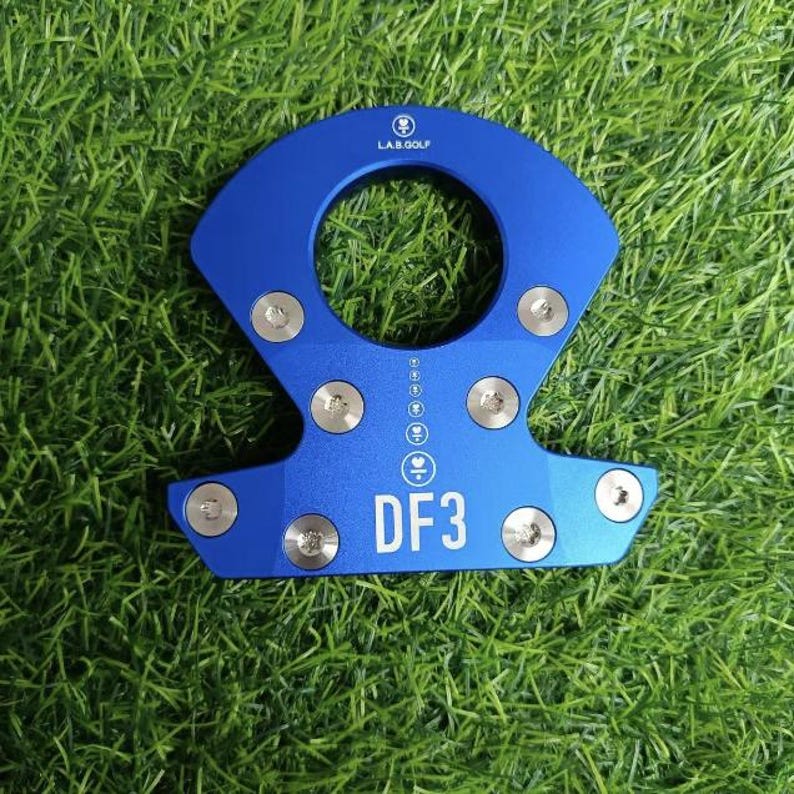 Op de afbeelding: Een blauw metalen golfclubaccessoire met de tekst "DF3" in het wit. Het accessoire heeft een cirkelvormige opening en is bevestigd met zilveren schroeven. Het logo "LAB.GOLF" is bovenaan zichtbaar.