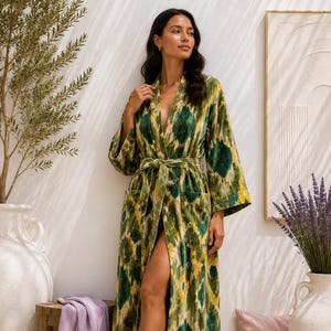 Puede incluir: Una bata larga hasta el suelo con un estampado ikat en verde, amarillo y blanco. La prenda tiene mangas largas y anchas, escote en V, dos bolsillos delanteros de parche y un cinturón de tela a juego en la cintura para el cierre.