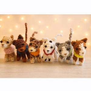 Könnte beinhalten: Eine Sammlung von sechs gehäkelten Hundefiguren in verschiedenen Farben und Mustern. Jeder Hund hat ein einzigartiges Design, einschließlich verschiedenfarbiger Kragen und Markierungen. Die Hunde sind auf einer Holzoberfläche mit weichen, verschwommenen Hintergrundlichtern angeordnet.