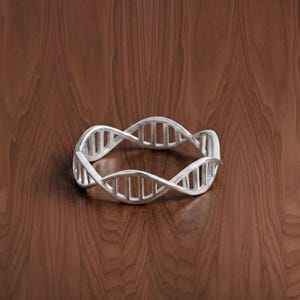 May include: A silver DNA helix bracelet. The bracelet is made of a shiny metal and is displayed on a dark brown wooden surface. The design features the iconic spiral structure of DNA, a symbol of science.