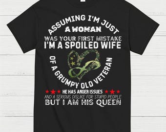 May include: Black t-shirt with white text that reads "Assuming I'm just a woman was your first mistake I'm a spoiled wife of a grumpy old veteran." A heart-shaped design with camouflage and stars is in the center.