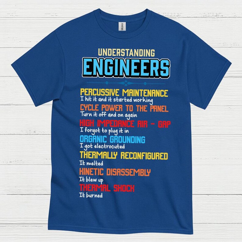 May include: A blue t-shirt featuring the text "UNDERSTANDING ENGINEERS" in white and blue. The shirt lists humorous engineering problem-solving methods, such as "Percussive Maintenance" and "Thermal Shock."