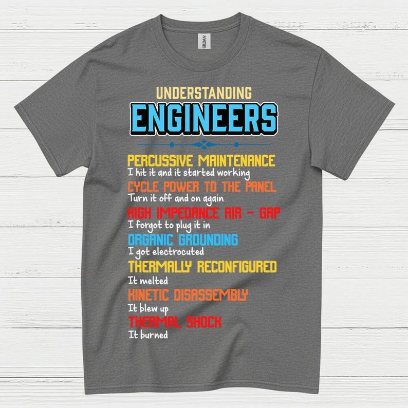 May include: A grey t-shirt featuring the text "UNDERSTANDING ENGINEERS" in blue and white. The shirt has a humorous list of engineering troubleshooting steps printed below in various colours. A fun gift.