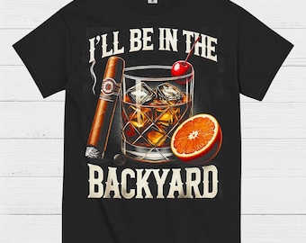 May include: Black t-shirt featuring a graphic of a cocktail with ice cubes, a cigar, and an orange slice. The text "I'll Be In The Backyard" is printed in white. The design is a vintage style.