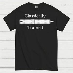 May include: Black t-shirt with the words "Classically Trained" above and below a graphic of a slide rule. The slide rule is white with black and gray details. The shirt is a Gildan brand.
