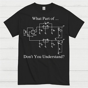 May include: Black t-shirt with a white schematic diagram and the text "What Part of... Don't You Understand?" The design features circuit symbols and labels, ideal for electronics enthusiasts.