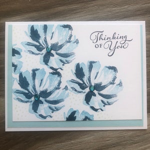May include: A white card with a blue floral pattern and the text "Thinking of You".