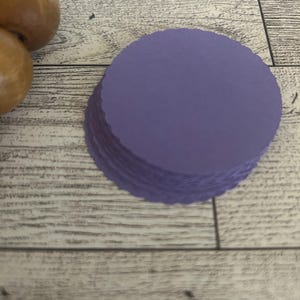 May include: A stack of purple paper circles with scalloped edges.