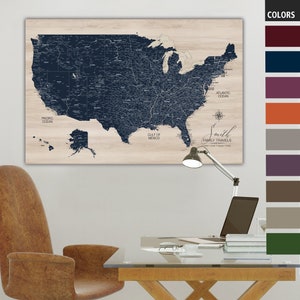 May include: A blue and white US map with a woodgrain background. The map is mounted on a wall above a desk with a lamp and a laptop. The map is labeled with the names of the oceans and the Gulf of Mexico. The text "Smith Family Travels" is written in a cursive font at the bottom of the map.