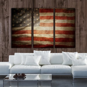 May include: A three-panel canvas print featuring a distressed American flag design. The flag is red, white, and blue with a faded, vintage look. The canvas is hung on a wood wall.