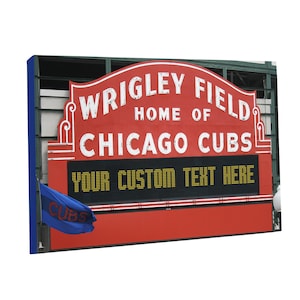 May include: A red sign with white lettering that reads "WRIGLEY FIELD HOME OF CHICAGO CUBS." Below the text is a black display that says "YOUR CUSTOM TEXT HERE." A blue flag with "CUBS" is on the left.
